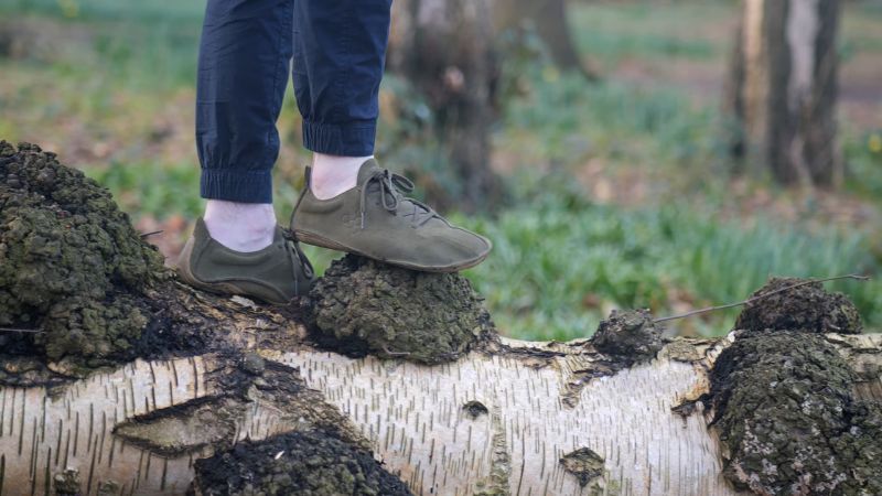 osoba stoji u barefoot cipelama na neravnom stablu u šumi