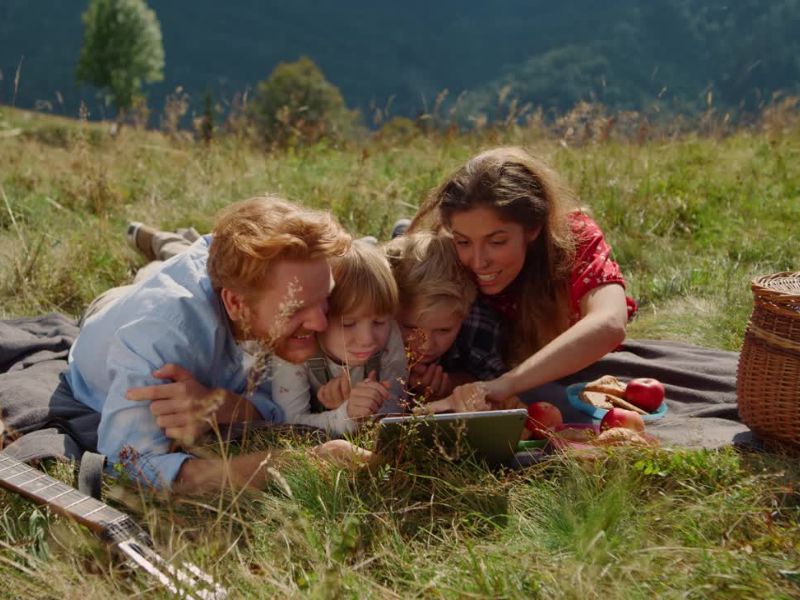 porodica na pikniku gleda u tablet