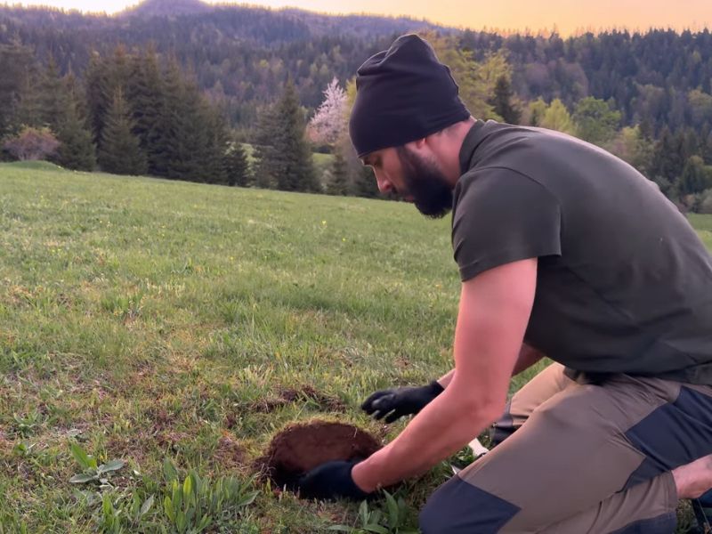 čovek kopa rupu na planini