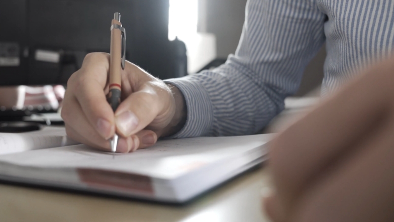 Čovek zapisuje plan za pokretanje malog biznisa u rokovnik