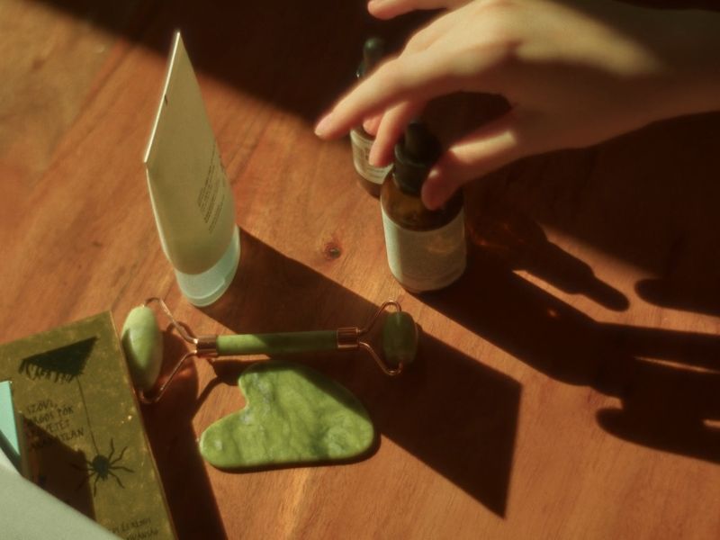 prikaz stola sa prirodnom kozmetikom i devojke koja uzima serum