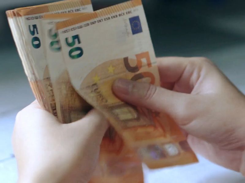 osoba drži mnoogo novčanica od 50e u ruci