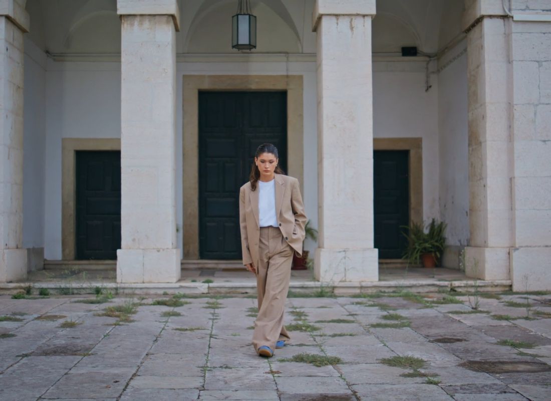 devojka šeta ulicom u elegantnom odelu i beloj majici