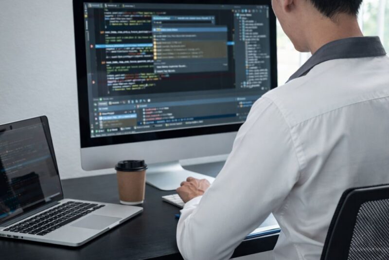 Osoba radi na izradi web sajta na računaru koristeći kod i razvojno okruženje