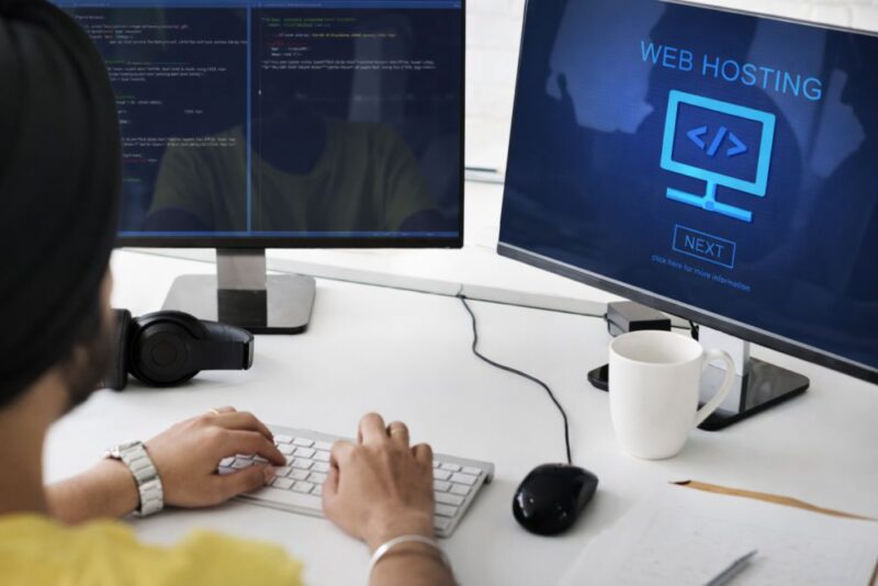 Osoba radi za računarom dok je na ekranu prikazan web hosting i programski kod