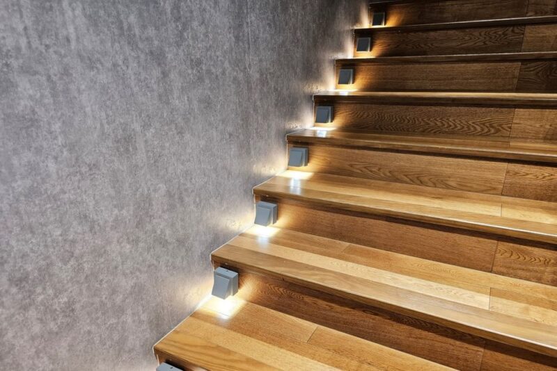 Unutrašnje stepenište sa drvenim oblogama i diskretnim LED osvetljenjem uz zid