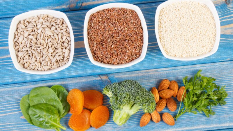 Raznovrsne namirnice bogate vlaknima poput semenki, povrća, badema i suvog voća na plavoj podlozi